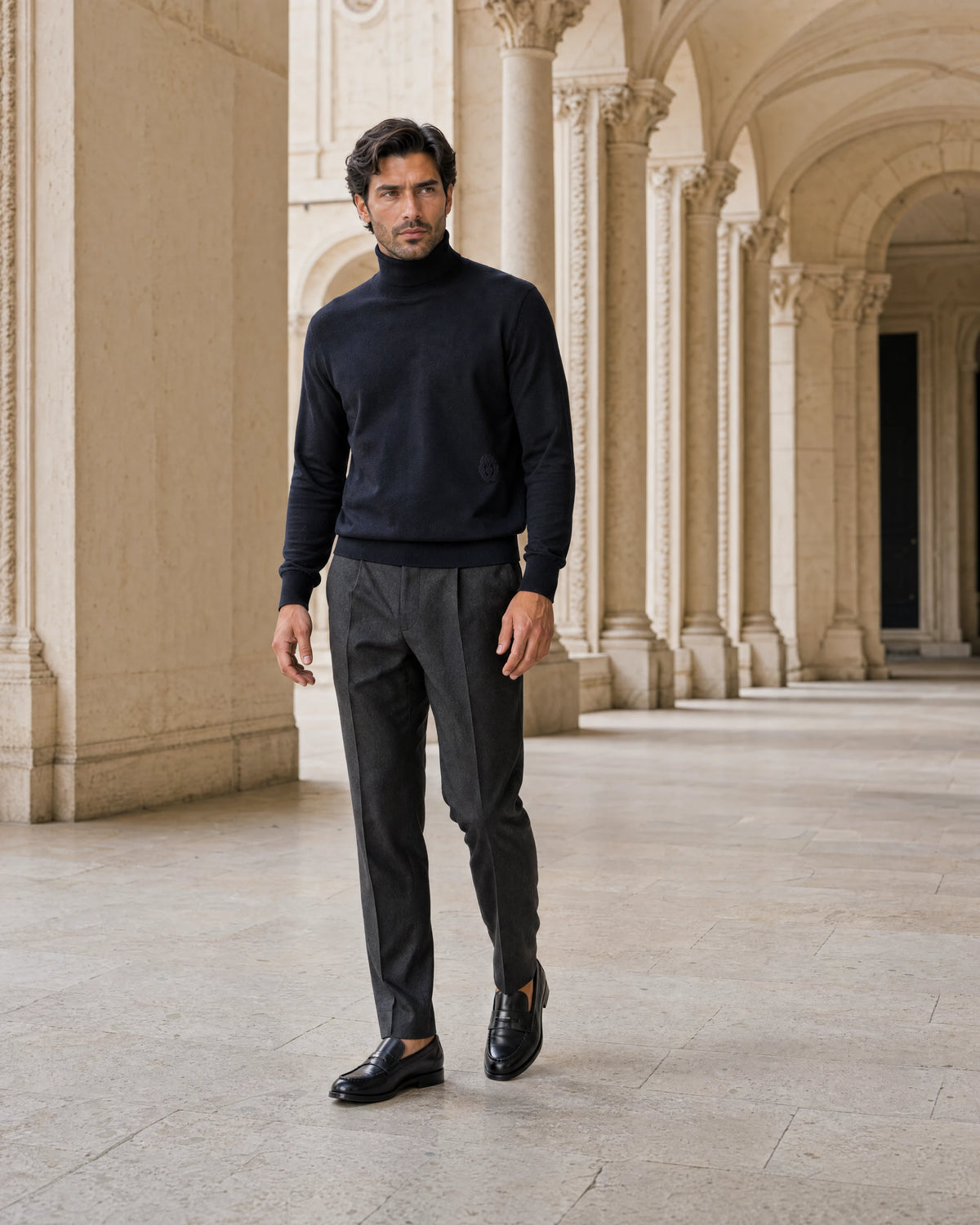 Man wearing black leather loafers and charcoal trousers in an open Italian arcade